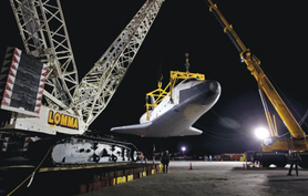 a photo of the space shuttle lifted by two cranes